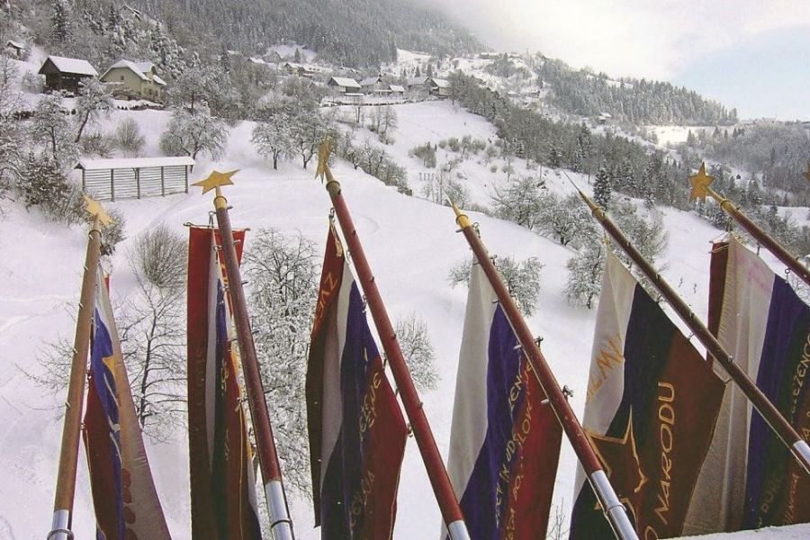 Borčevski prapori so uperjeni proti današnjim Dražgošam. Vir slike: Družina. Foto: Ivo Žajdela.